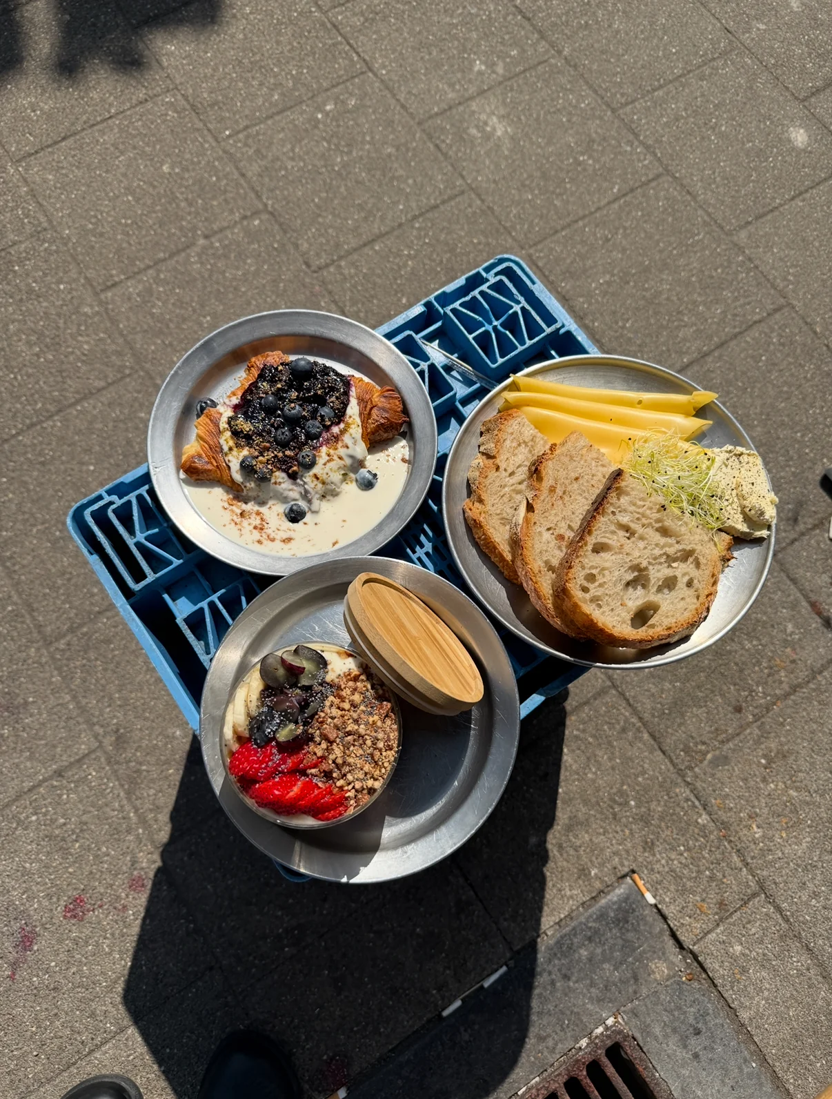 Flat-lay of plant-based plates — croissant with berries, sourdough with cheese and a yogurt bowl