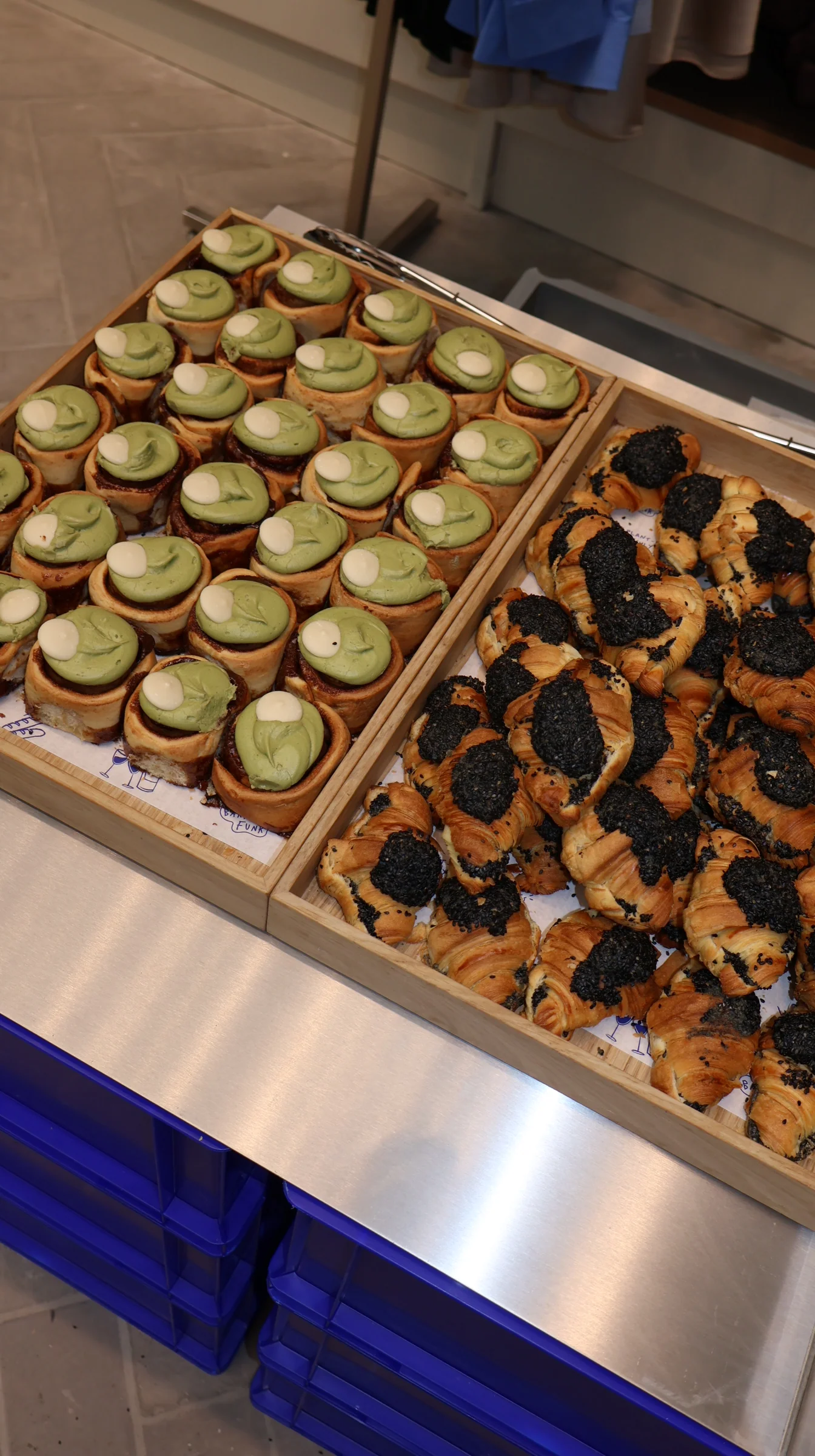 Trays of matcha tarts and black sesame croissants prepared for a catering spread